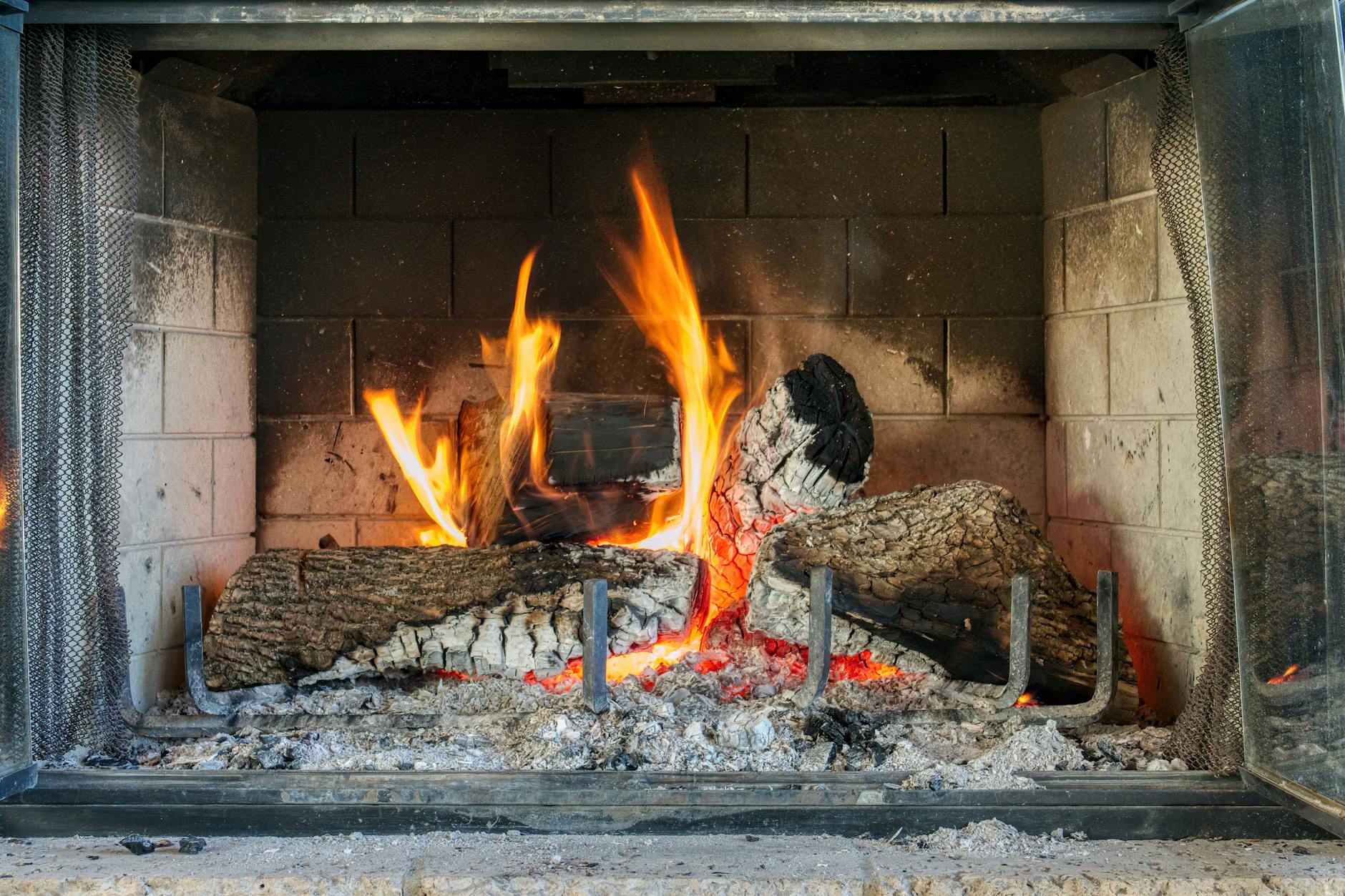 Warm and inviting indoor fireplace with glowing firewood and vibrant flames.